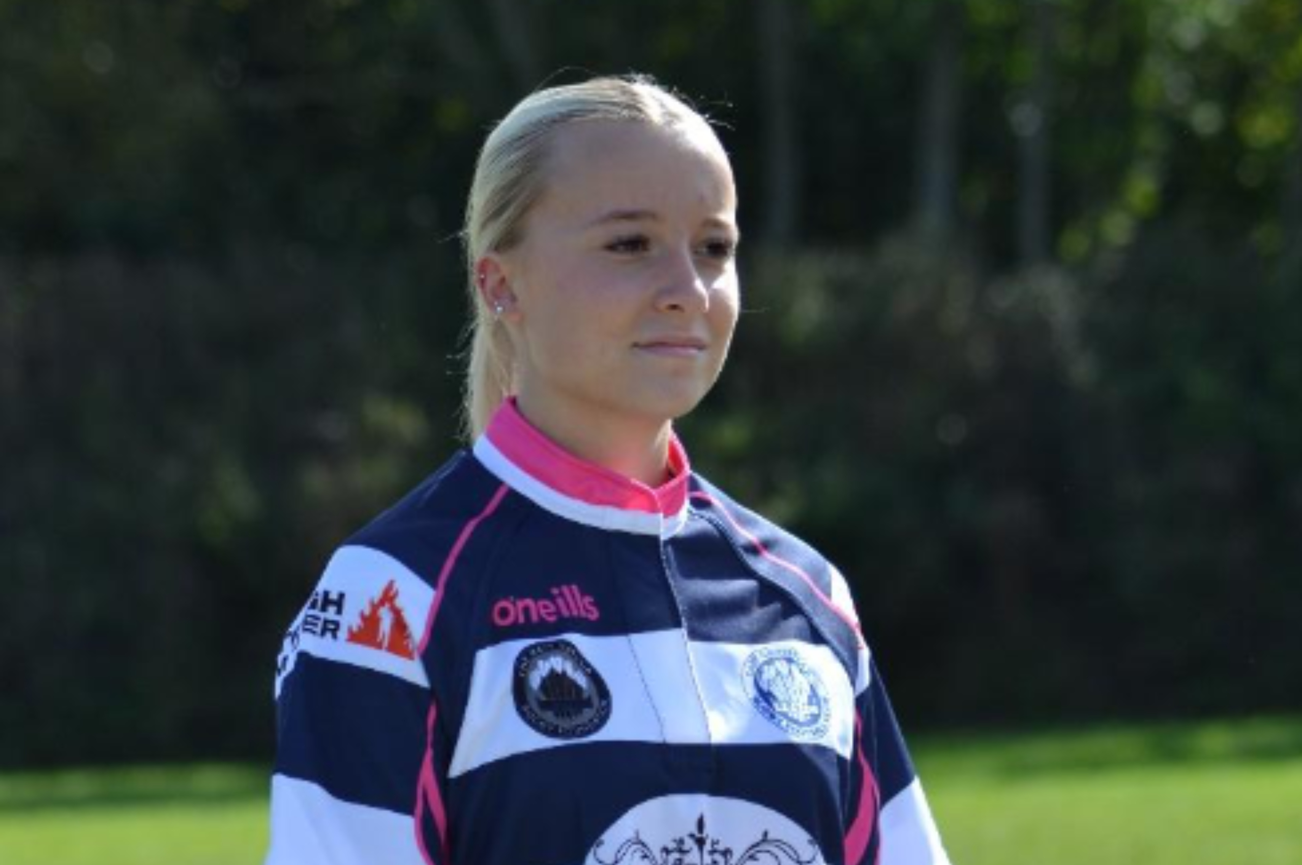 A girl wears a striped rugby shirt with the Barwells Wealth logo on the front.