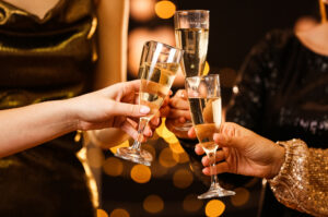 Three people toast their champagne glasses.