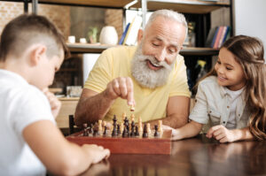Grandad playing chess with his grandson and granddaughter