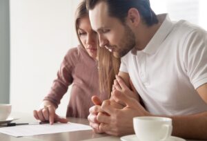 A couple sits at a desk reading a financial statement with a cup of tea.