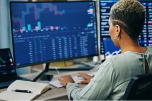 A woman reads a stock market graph from a computer screen.